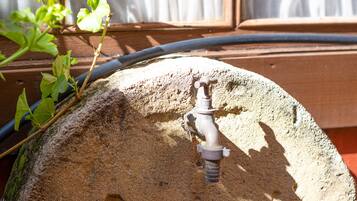 Ein Wasserspiel mit Wasserhahn auf einer Steinfläche, umgeben von Grün.