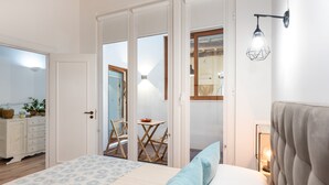 Ein Schlafzimmer mit Bett, Nachttischlampe und Blick auf einen Außenbereich mit Tisch und Stühlen.