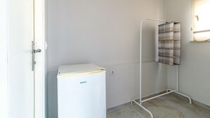 A compact room with a white refrigerator, a metal rack with a plaid pattern, and a door. - Şişli Suites (Istanbul)