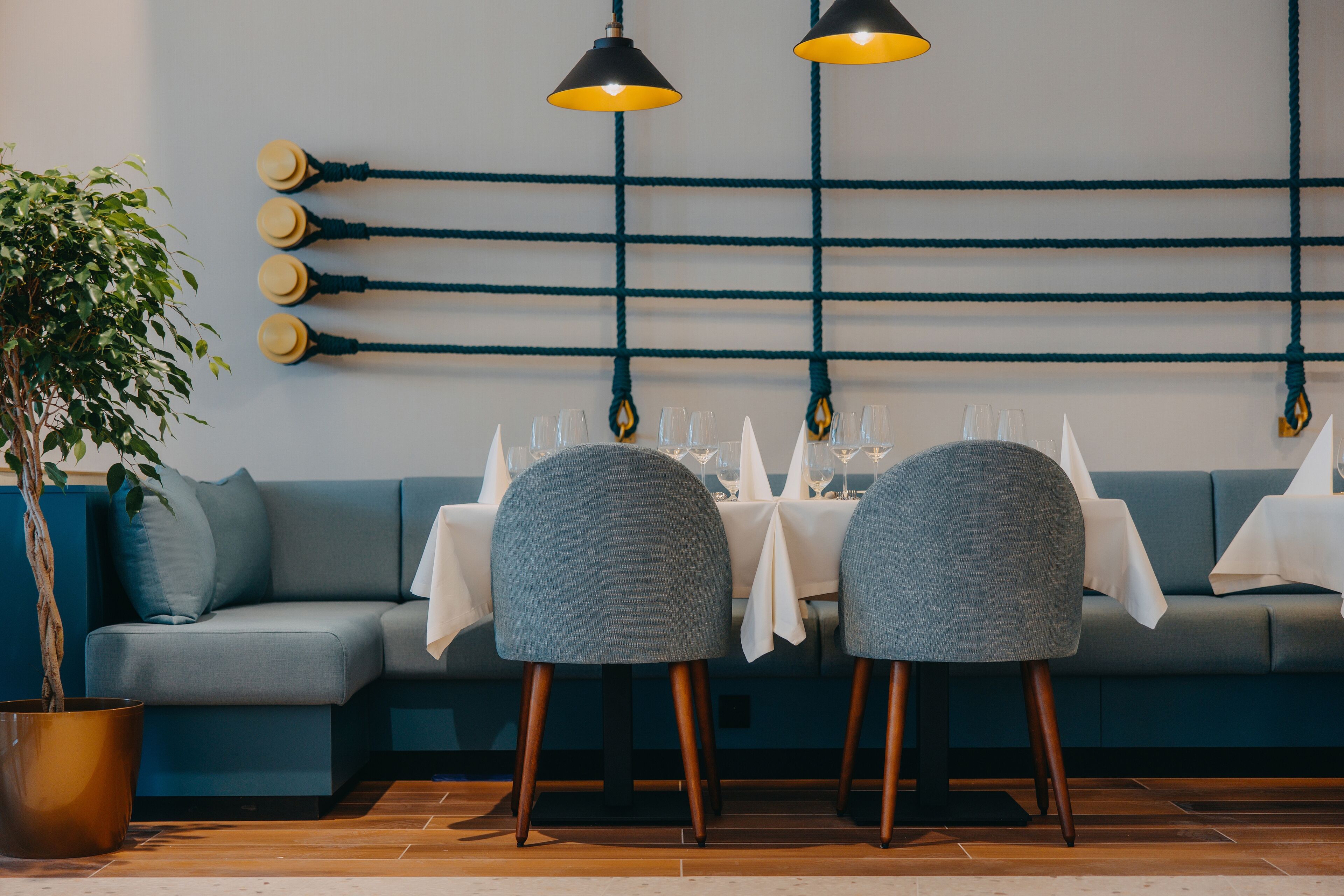 A dining area with a sofa, tables, chairs, and hanging lights.