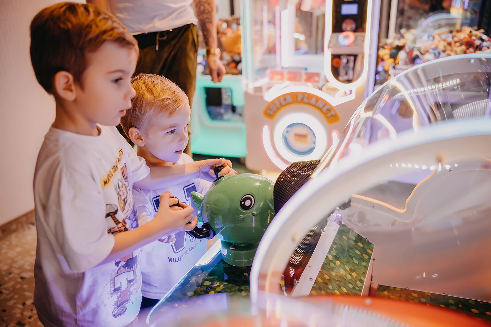Children playing with a green robot toy at a carnival game machine.