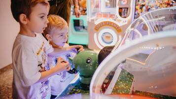 Children playing with a green robot toy at a carnival game machine.