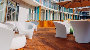 Un pont de navire de croisière moderne, doté de plusieurs niveaux de balcons, d’espaces de détente en plein air et d’une zone de pont en bois.