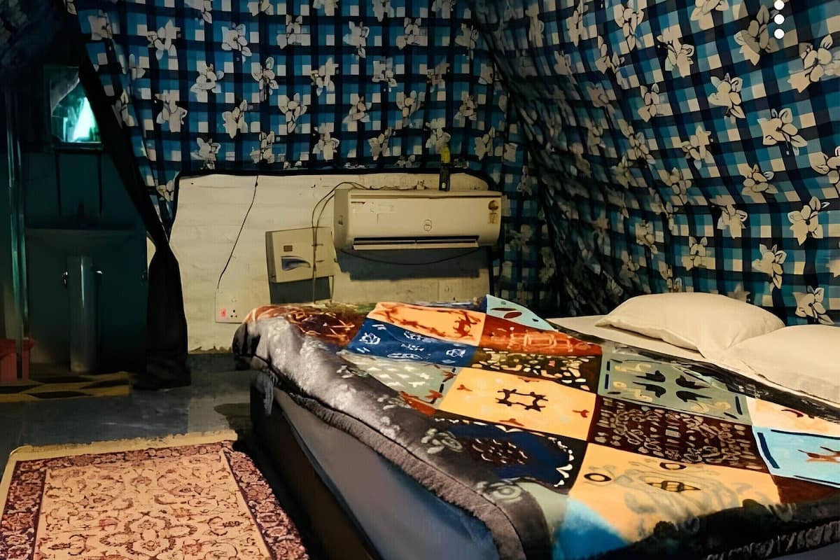 A room with a bed, a rug, and a patterned wall.