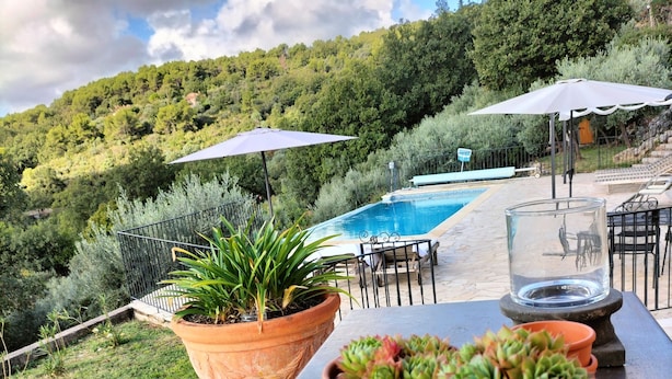 Ein Außenpoolbereich mit Terrakottapflanzgefäßen mit Sukkulenten, einem Billardtisch und Gartenmöbeln.