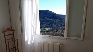 Ein Schlafzimmer mit einem Bett, einem Heizkörper, einem Fenster mit Bergblick und einem hölzernen Kleiderbügel.