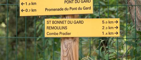 Un cartel de madera con indicaciones direccionales hacia Pont du Gard, Promenade du Pont du Gard, St Bonnet du Gard, Remoulins y Combe Pradien.