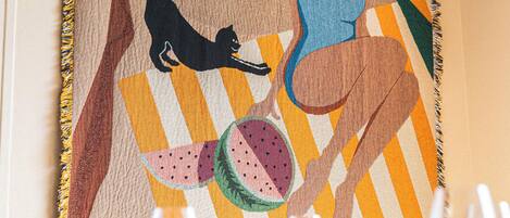 A dining table set with plates, glasses, and a colorful table runner with a tree and a cat.