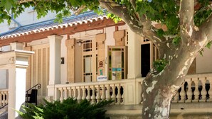 Un edificio con recepción, un balcón con barandillas y un árbol en primer plano.