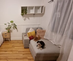 Relax in this serene space with a light grey sofa, a small plant, and a cozy nightstand.