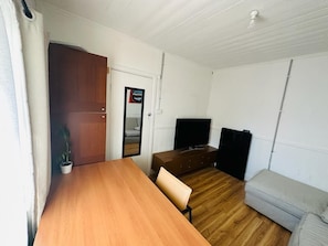 Cozy space with a dining table, chair, and potted plant, perfect for a compact living area or guest room.
