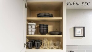 A kitchen cabinet with shelves holding black and white bowls, cups, and glasses. - 735 NW 30th St, Apt 11 OKC (Oklahoma City)