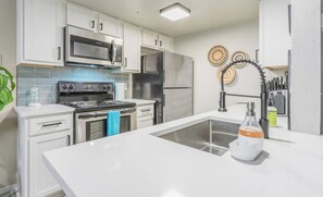 Una cocina moderna con armarios blancos, electrodomésticos de acero inoxidable y una isla central con fregadero.
