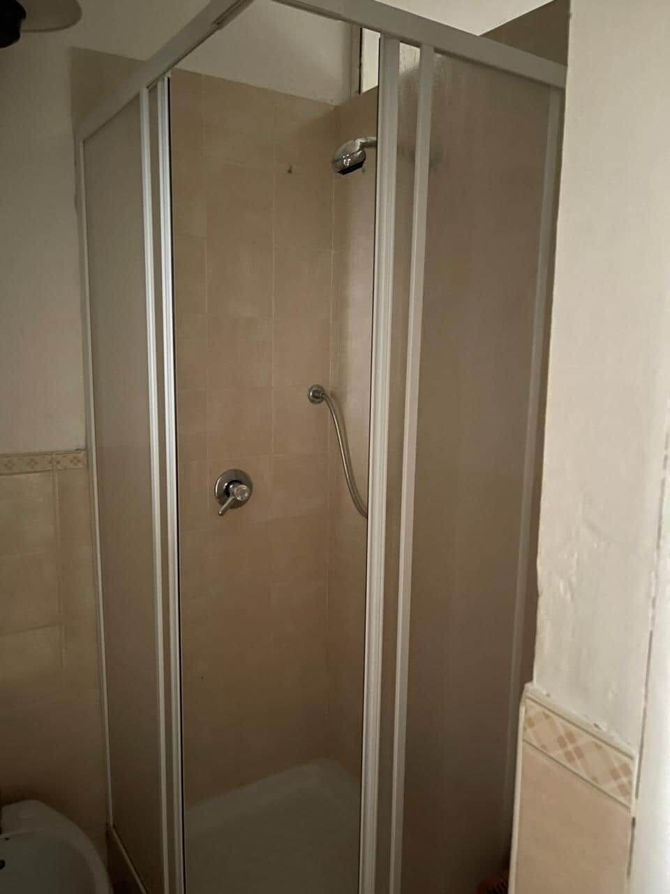 A walk-in shower with a glass door and a showerhead.