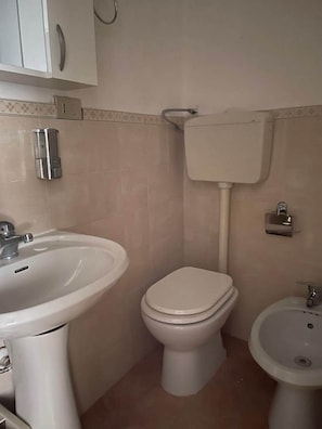 A bathroom with a toilet, sink, and bidet.