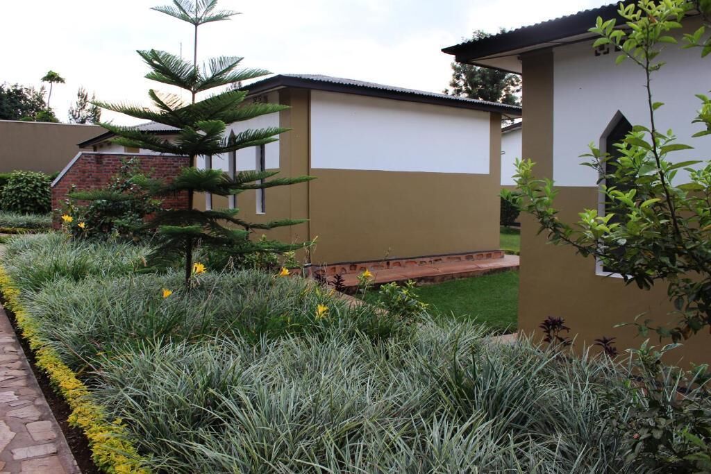 Un edificio de fachada color beige con un pequeño jardín y un sendero.