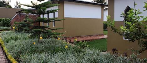 Un edificio de fachada color beige con un pequeño jardín y un sendero.