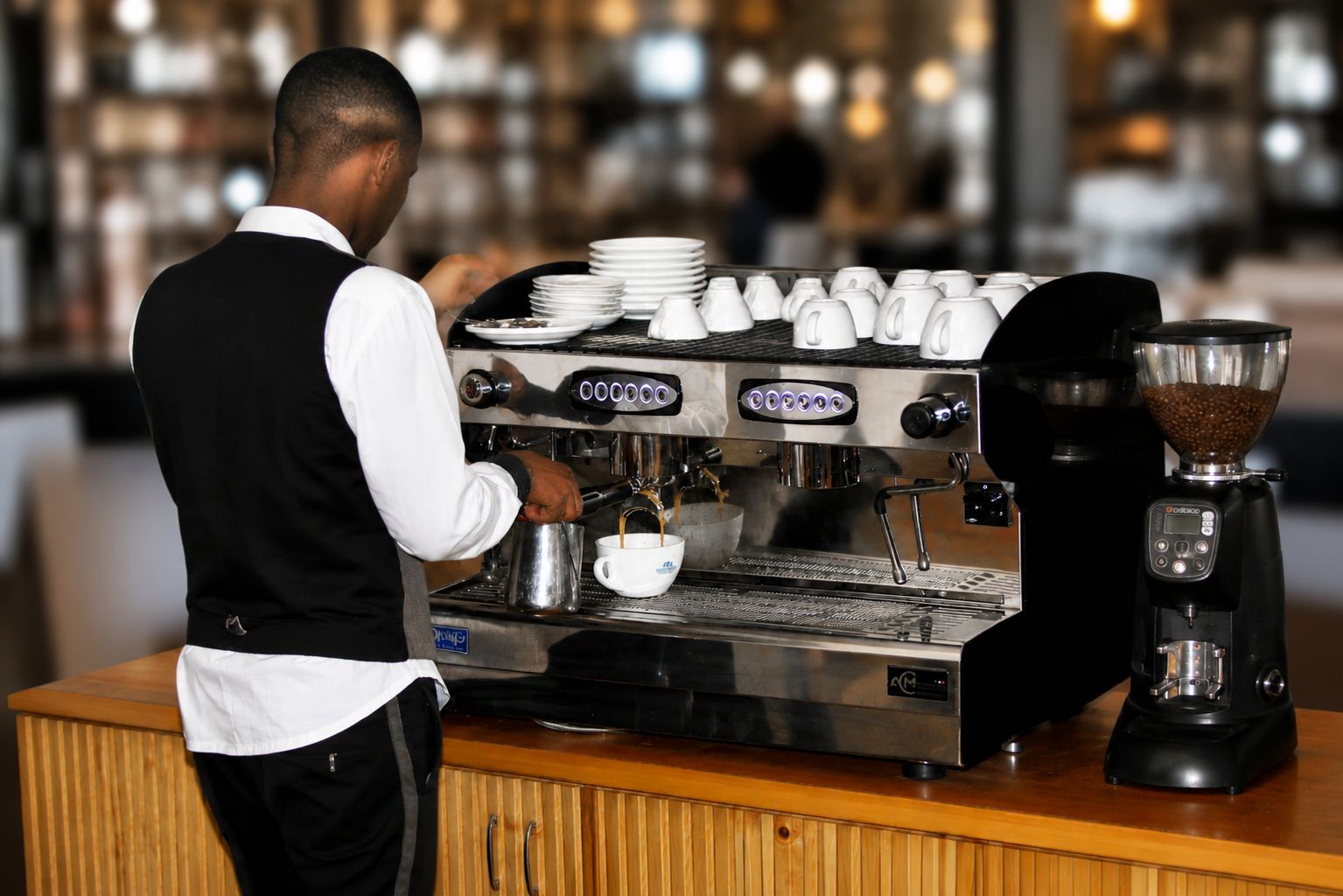 A barista at a coffee machine in a cafe setting.