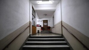 Un couloir au sol de marbre qui mène à une porte au fond.