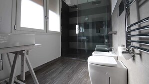 Une salle de bain moderne avec une douche à parois de verre, des toilettes blanches et un lavabo doté d’un porte-serviettes.