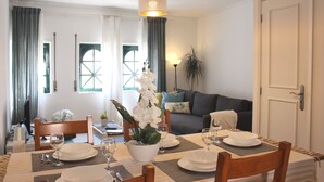 Een eetgedeelte met een tafel voor vier personen, een bank en een deur aan de rechterkant.