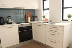 Enjoy cooking in this well-lit kitchen with oven, sleek cabinetry, and kettle.