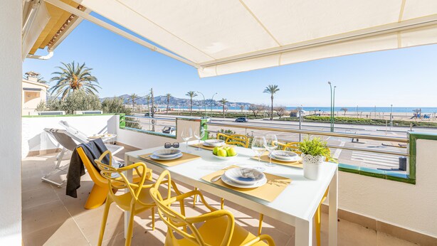 Een balkon met een eettafel, met uitzicht op een kustweg en strand.