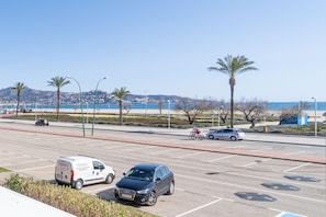 A parking lot with a white van and a dark-colored SUV, a cyclist, and a parked car. - Sea view apartment with 2 bedrooms (Empuriabrava)