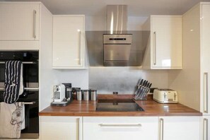 Une cuisine moderne avec des armoires blanches, des appareils en acier inoxydable et un plan de travail en bois.