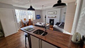 Una cocina compacta con una isla central, armarios de madera y un comedor con sillas y una mesa.