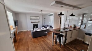 Una cocina moderna con encimera de madera, taburetes negros y horno empotrado.