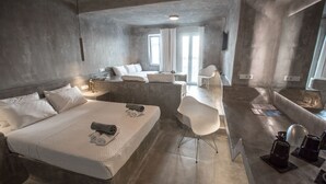 A modern hotel room with a large bed, a desk, and a seating area.