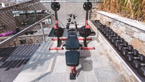 A stone wall with a bench and dumbbells arranged on a patio.