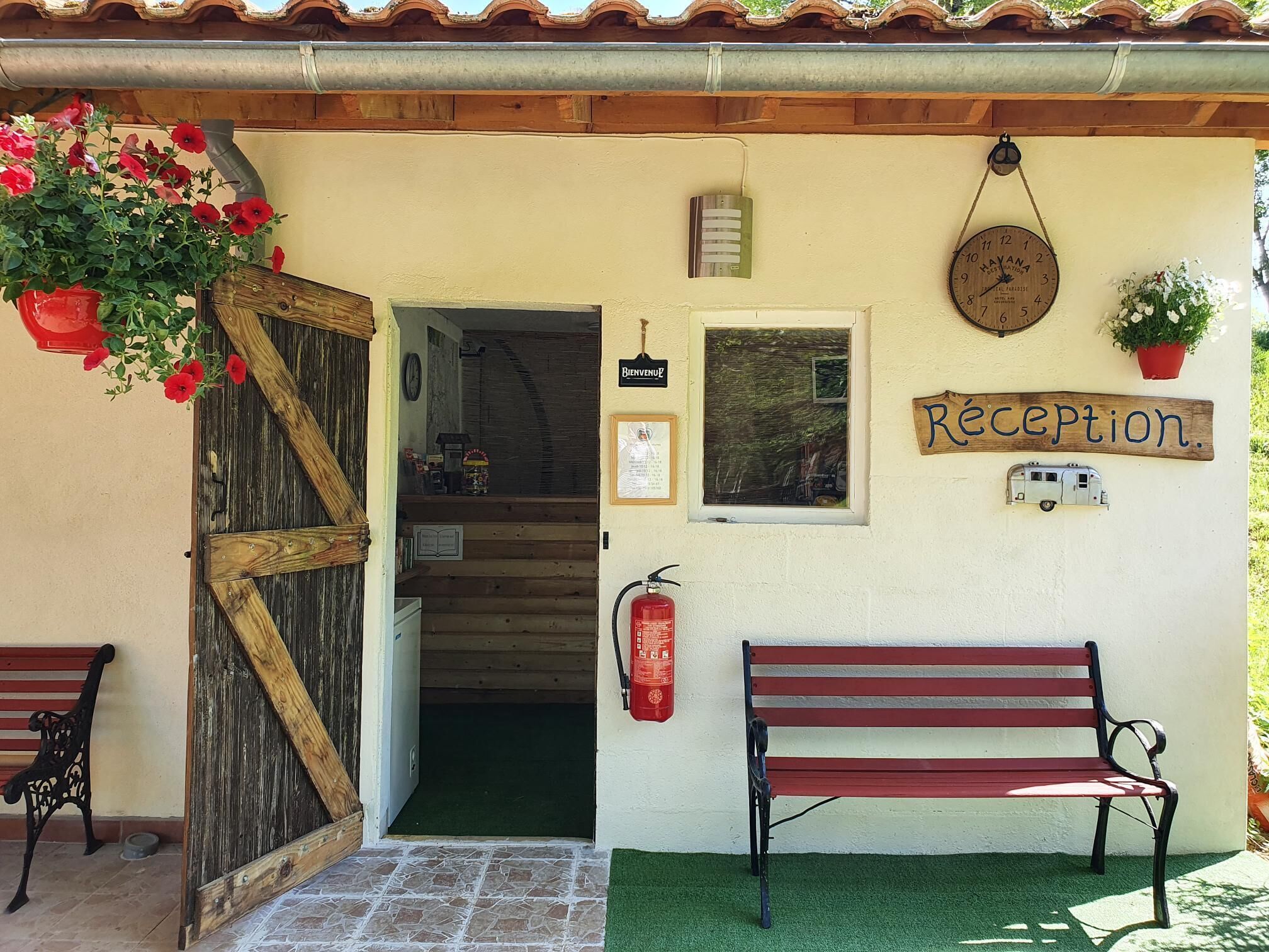 A reception area with a wooden bench, a red fire extinguisher, and a sign that reads "Réception."
