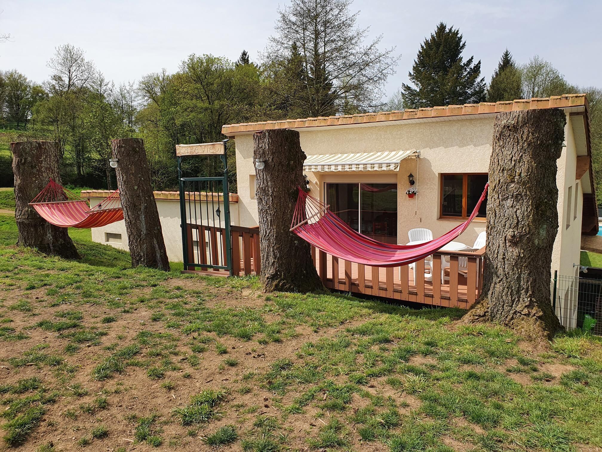 A small, single-story building with a sloped roof and a covered patio area. There are hammocks attached to the trees surrounding the building.