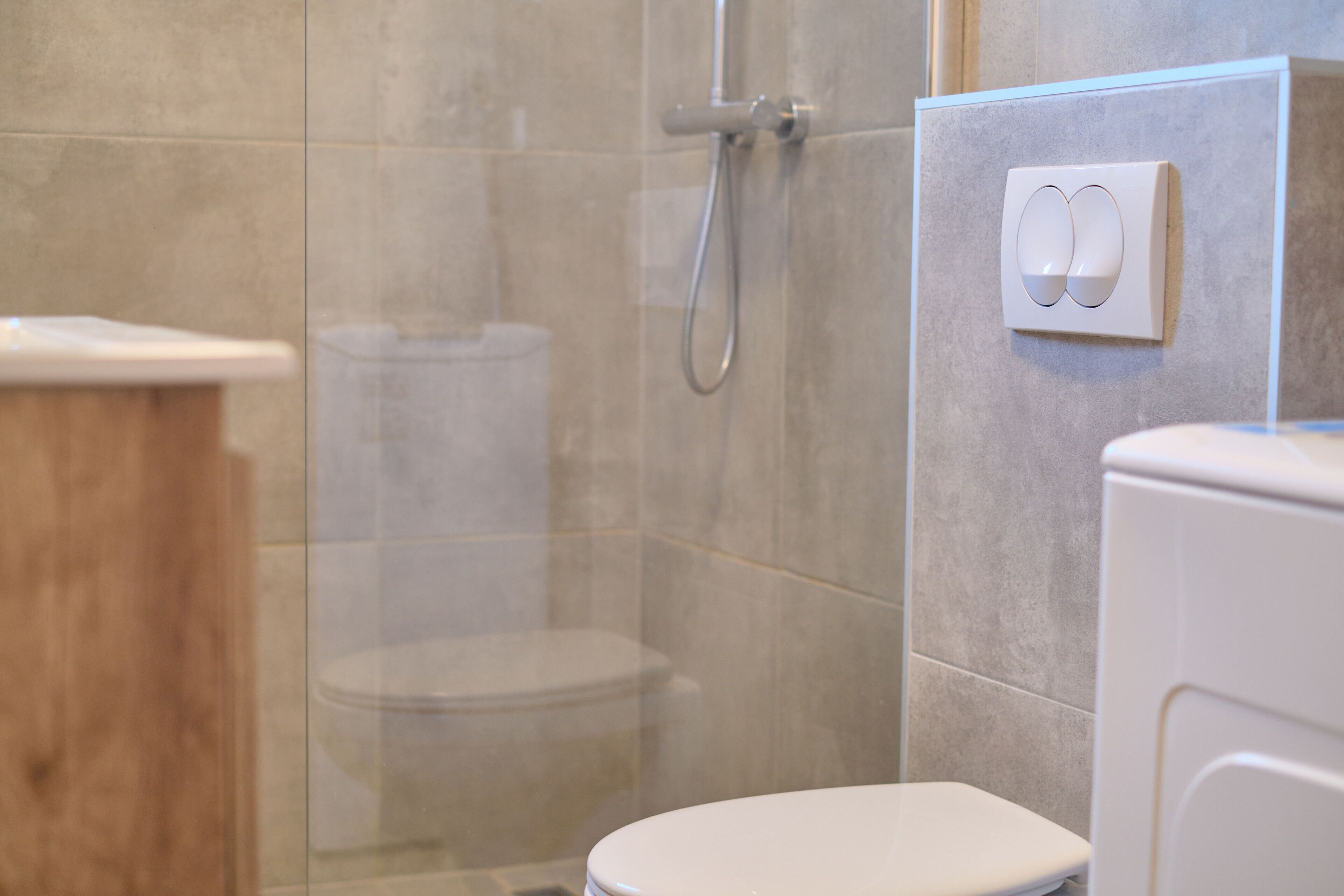 Une salle de bain dotée d’une douche à parois de verre, de toilettes et d’un panneau de commande fixé au mur.