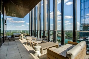Una terraza moderna en la azotea con amplias ventanas, mobiliario exterior y vistas panorámicas de la ciudad.