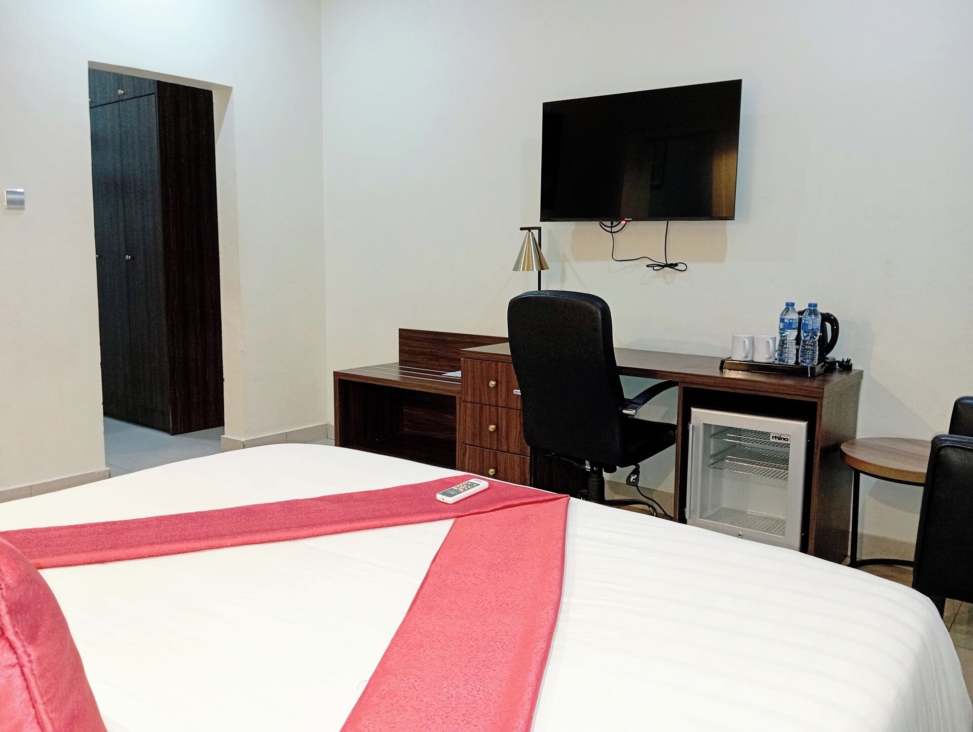 Een hotelkamer met een bed, een bureau, een stoel, een televisietoestel en een minibar.