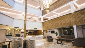 A hotel lobby with a reception desk, seating area, and a coffee shop. - BON HOTEL PLATINUM (Enugu)