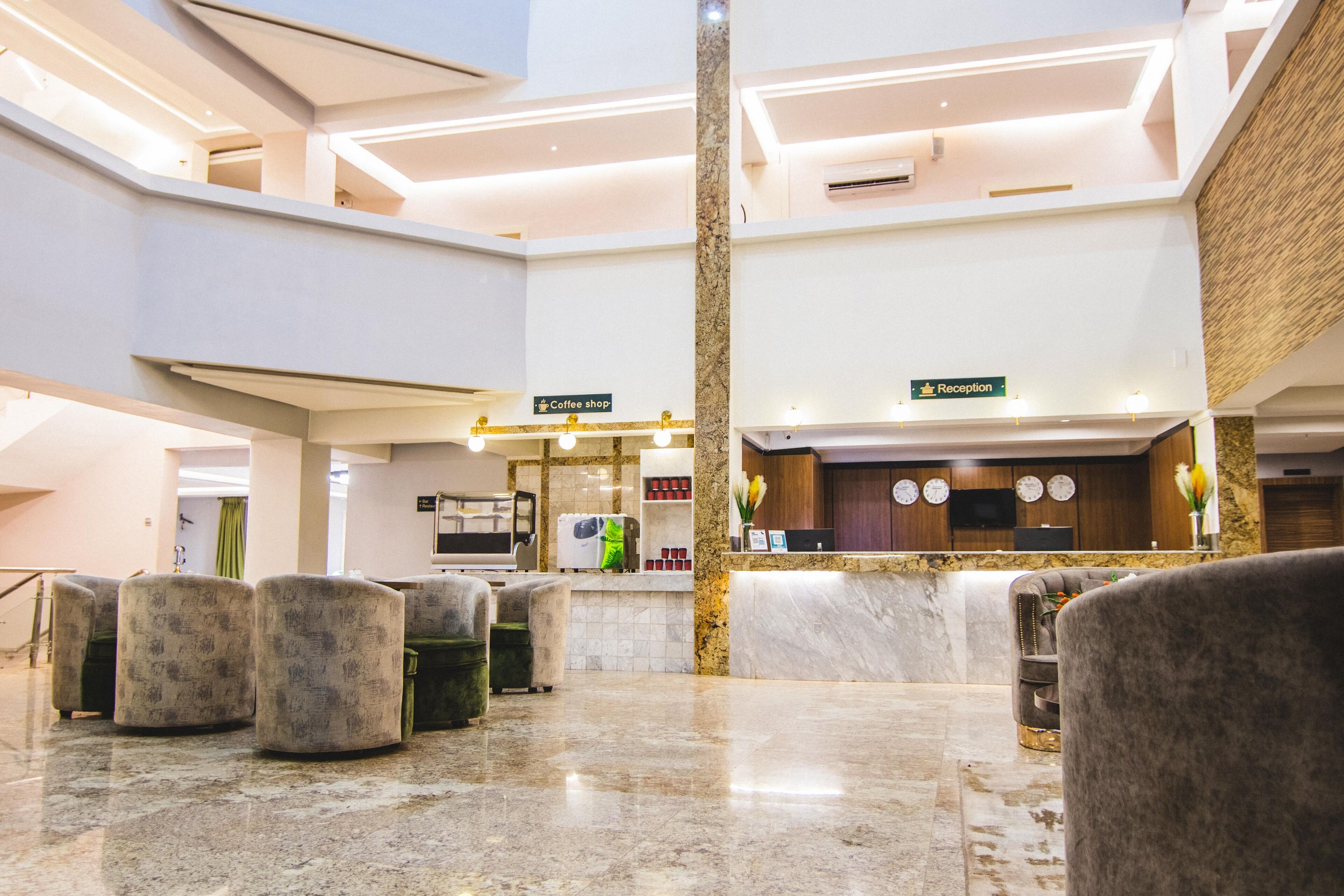 A hotel lobby with a reception desk, a coffee shop, and seating areas.
