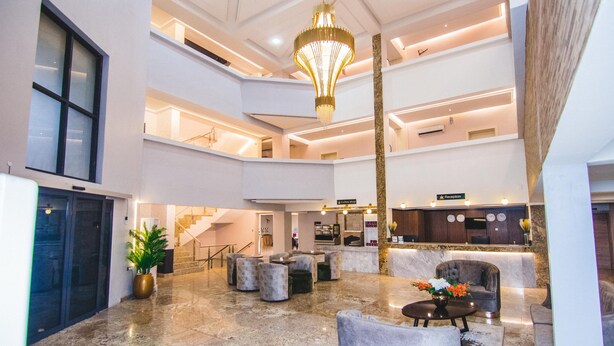 A spacious lobby with a high ceiling, a reception desk, seating areas, and a staircase leading to upper floors. - BON HOTEL PLATINUM (Enugu)