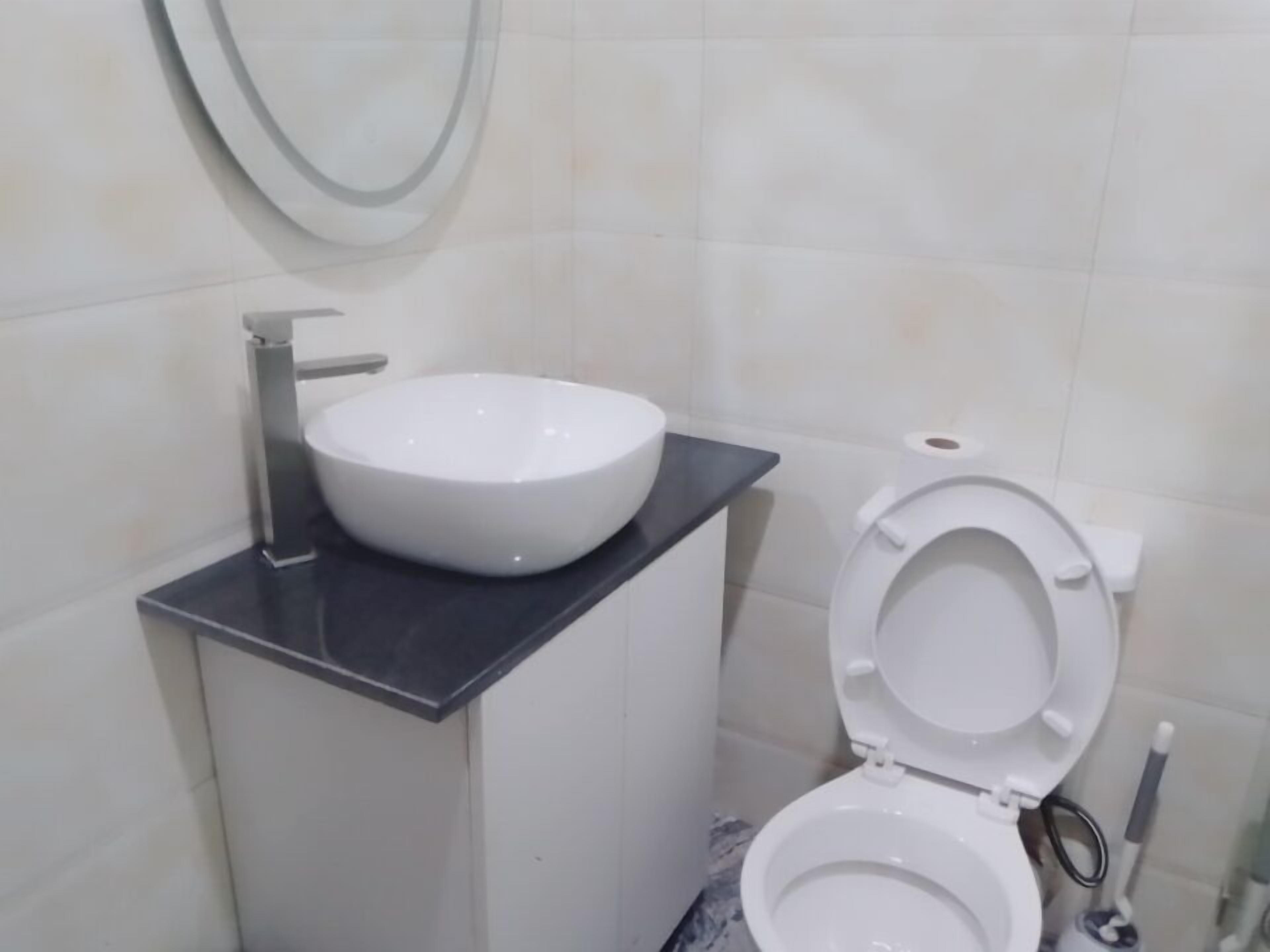 A bathroom with a white sink, toilet, and a mirror on the wall.