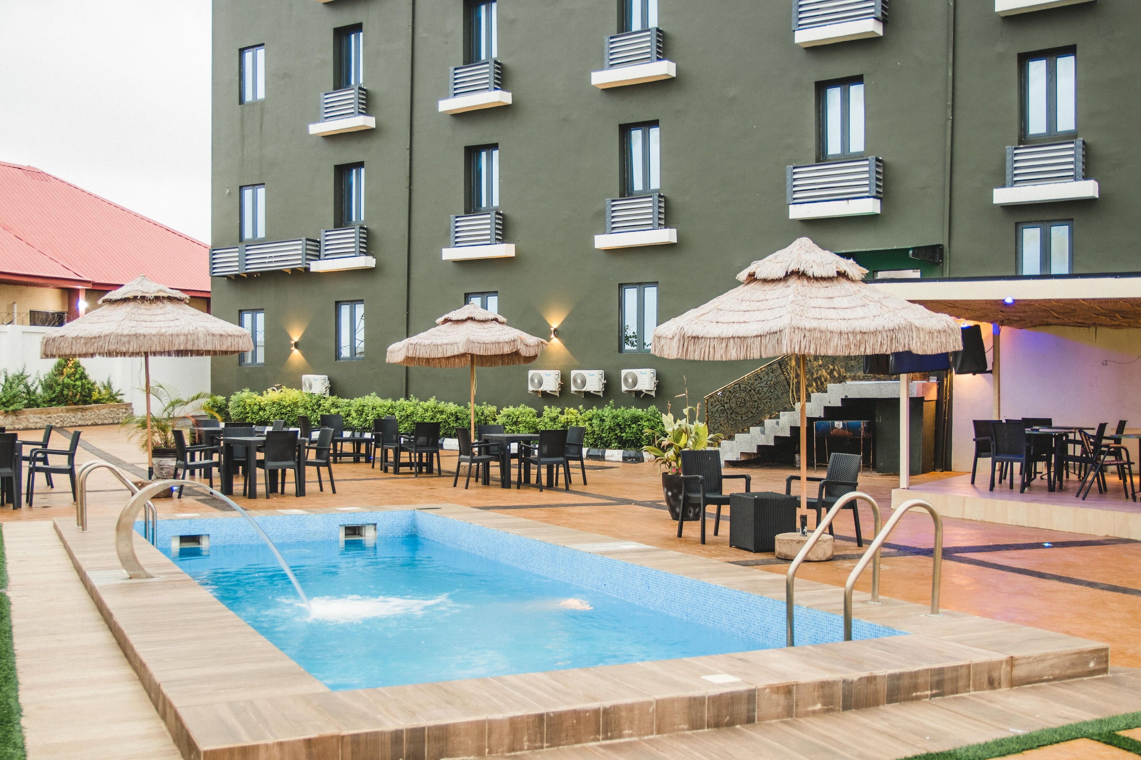 Una piscina con un solarium in legno, circondata da sedute all'aperto e ombrelloni.