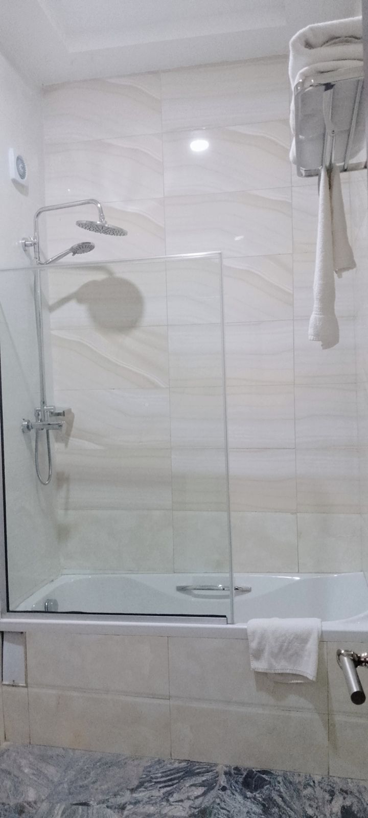 A bathroom with a glass-enclosed shower, a bathtub, and a towel rack.