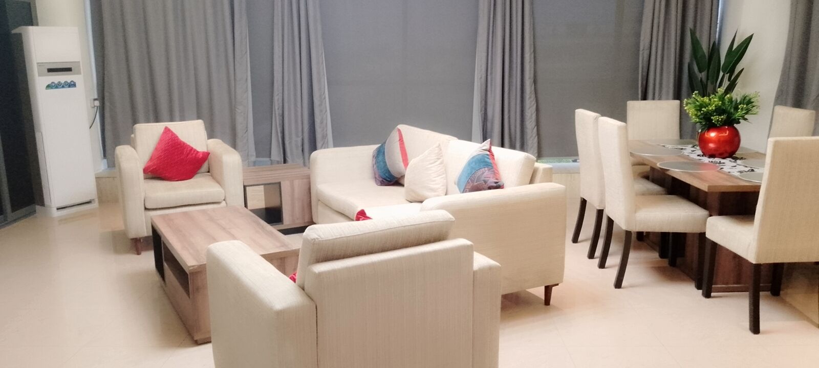 A living room with a sofa set, a coffee table, and a dining area with chairs and a table.