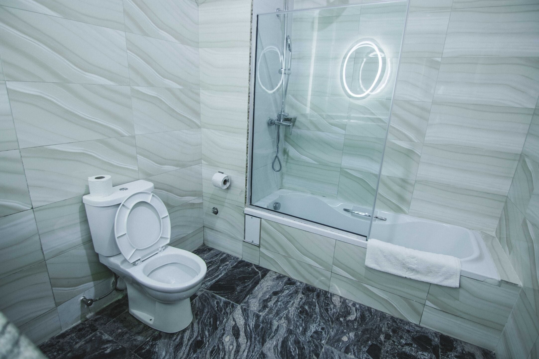 Un baño con inodoro, ducha con cerramiento de vidrio y bañera.
