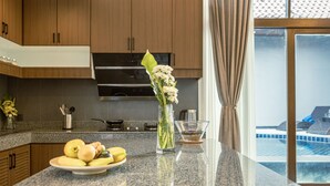 Eine Küche mit Granit Arbeitsplatten, einem Edelstahlherd und Holzschränken. Auf der Arbeitsfläche steht ein Teller mit Obst und eine Vase mit Blumen.