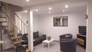 Un saló modern amb escala, un sofà, una taula de centre i un televisor.
