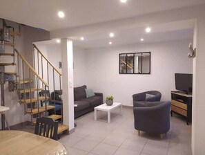 Stylish living room with a staircase, sofas, and a TV.