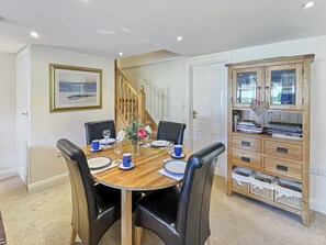 A dining area with a round wooden table, black chairs, and a cabinet with drawers.